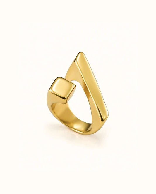 A polished gold ring with a modern, angular triangular design and a square-cut side detail, shown on a clean off-white background.