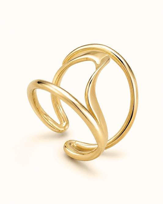 A polished gold abstract wrap ring with a fluid, flowing design, photographed on a clean off-white background.