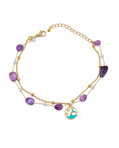 A gold-toned double-strand necklace featuring purple amethyst beads, small white pearl-like beads, and a circular gold charm with a turquoise mermaid design, displayed on a clean white background.