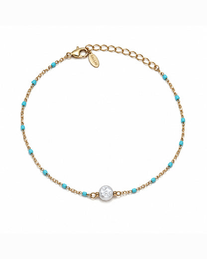 A delicate gold chain bracelet with small turquoise blue beads and a central round silver-toned charm, displayed on a clean white background.