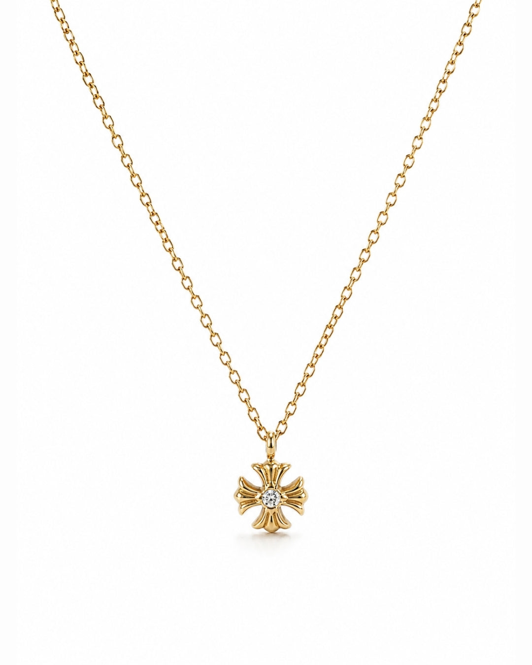A delicate gold chain necklace featuring a small gold cross pendant with a central clear gemstone, displayed against a solid white background.