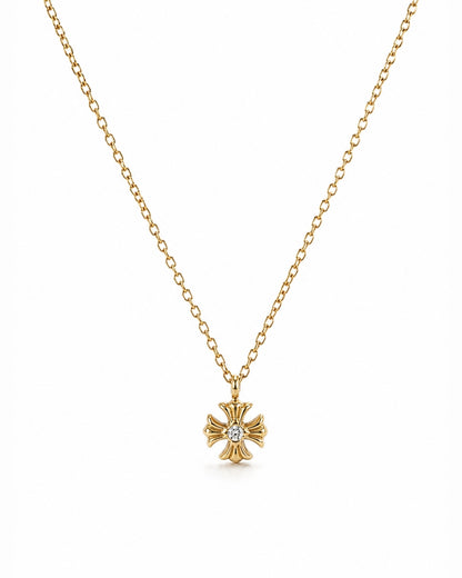 A delicate gold chain necklace featuring a small gold cross pendant with a central clear gemstone, displayed against a solid white background.