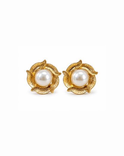 A pair of gold flower-shaped stud earrings with a central white pearl, set against a plain white background.