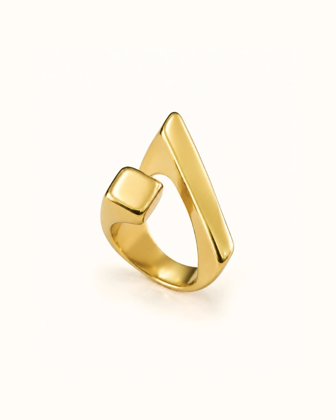 A polished gold ring with a modern, angular triangular design and a square-cut side detail, shown on a clean off-white background.