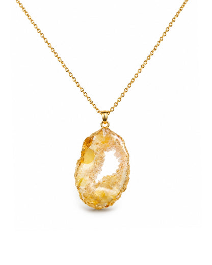 A gold chain necklace featuring an irregular, polished geode-style pendant with a natural yellow and cream-colored interior, shown against a plain white background.