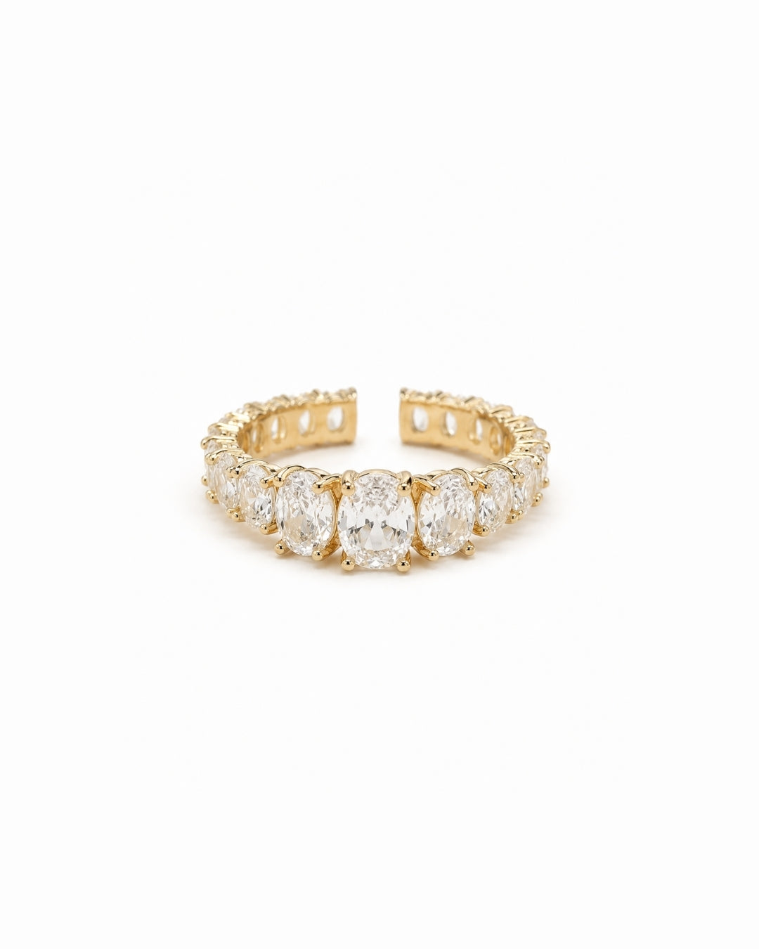 A yellow gold eternity ring featuring a row of oval-cut clear gemstones, shown on a plain white background.
