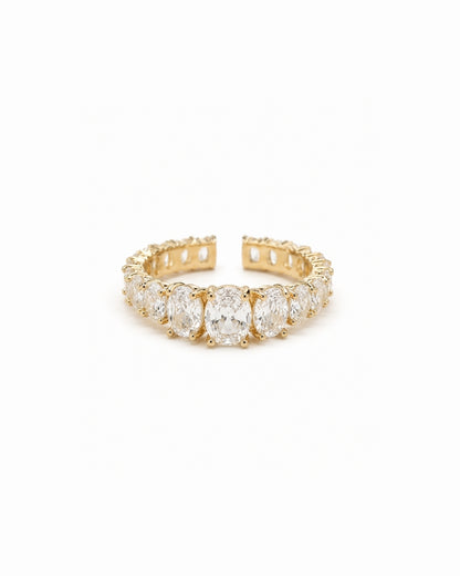 A yellow gold eternity ring featuring a row of oval-cut clear gemstones, shown on a plain white background.