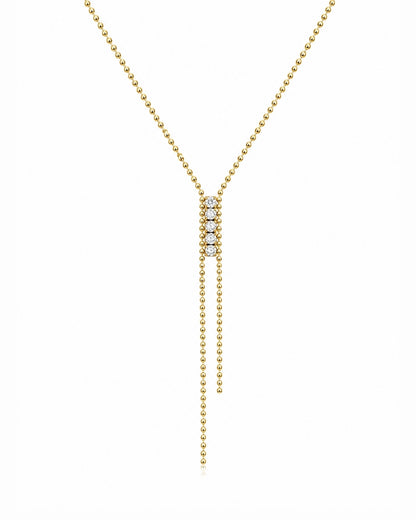 A delicate gold Y-necklace featuring a central cluster of small clear stones and two long dangling bead chains, shown on a plain white background.