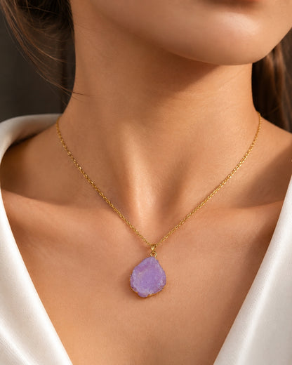 A gold chain necklace with a teardrop-shaped light purple daisy-cut gemstone pendant, shown worn on a model's neck.
