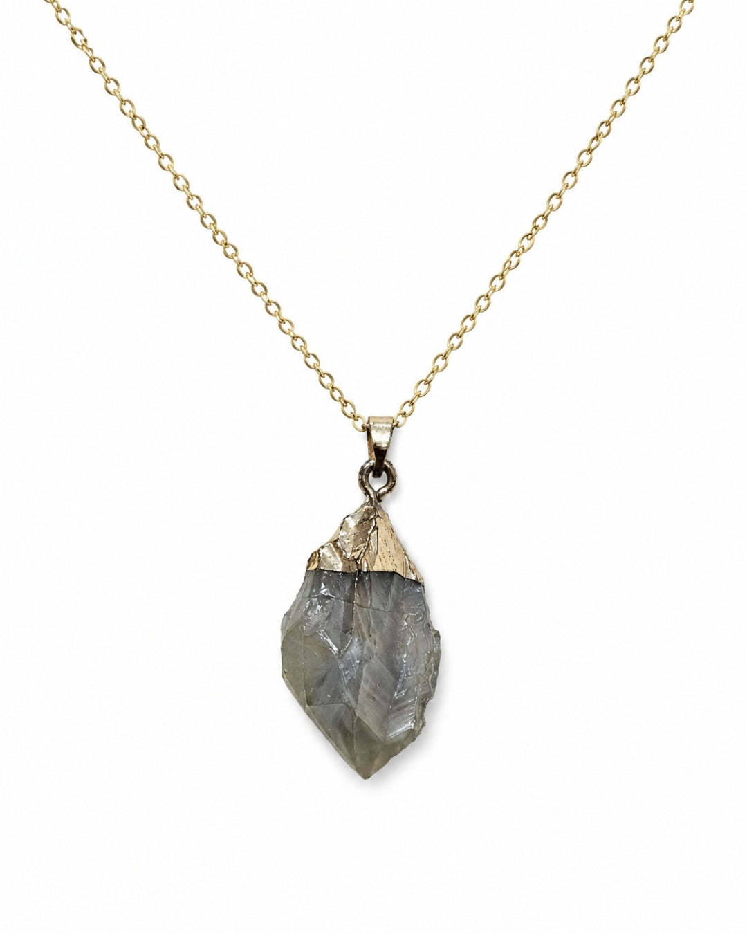 A gold chain necklace featuring a raw, faceted gray stone pendant with a polished gold cap, shown against a plain white background.