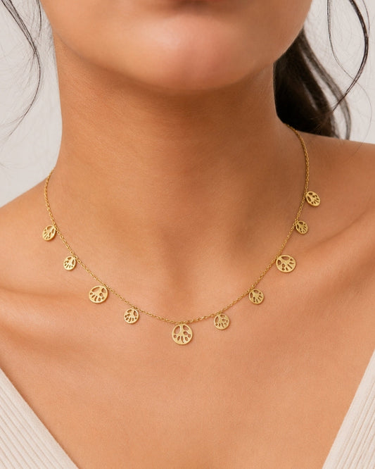 A close-up of a model wearing a delicate gold chain necklace with multiple small peace sign charms.