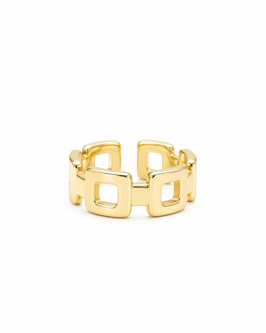 A gold geometric ring with a wide band composed of interlocking square links, shown on a plain white background.