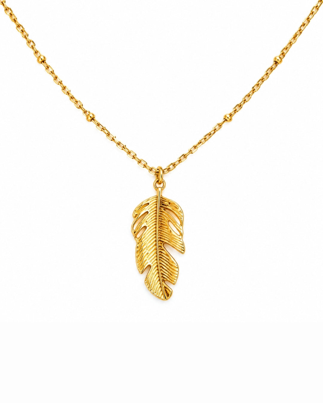 A gold chain necklace featuring a textured, leaf-shaped feather pendant, displayed against a solid white background.