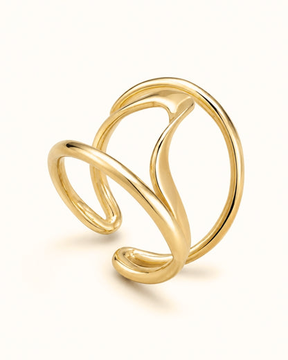 A polished gold abstract wrap ring with a fluid, flowing design, photographed on a clean off-white background.