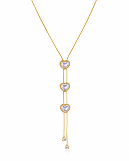 A gold Y-necklace featuring three vertical rows of heart-shaped pearl pendants, with a small clear crystal drop at the bottom, set against a plain white background.
