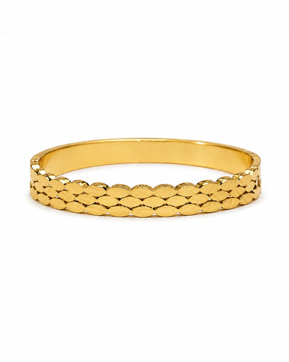 A gold bangle bracelet with a textured, overlapping scale-like pattern on the outer band, shown against a plain white background.