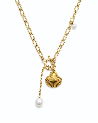 Gold chain necklace with a toggle clasp, a scallop shell charm, a dangling bead chain, and white pearl beads, shown on a plain white background.