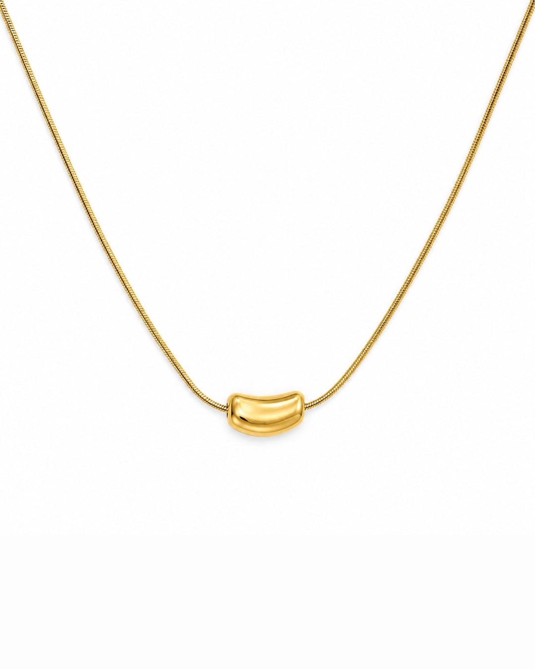 A gold chain necklace with a small, curved, polished gold bead pendant, shown against a plain white background.