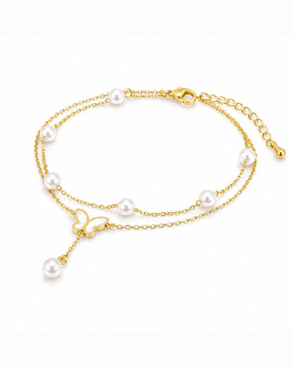 A delicate double-strand gold chain bracelet adorned with white freshwater pearls and a small gold butterfly charm, displayed on a clean white background.
