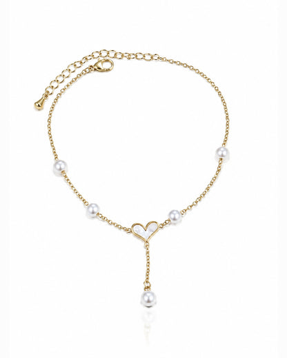A delicate gold chain anklet featuring white pearl beads spaced along the chain, a small open heart design at the center, and a dangling pearl charm, shown on a clean white background.
