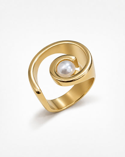 A gold spiral ring with a single white pearl set in the center, photographed on a clean white background.