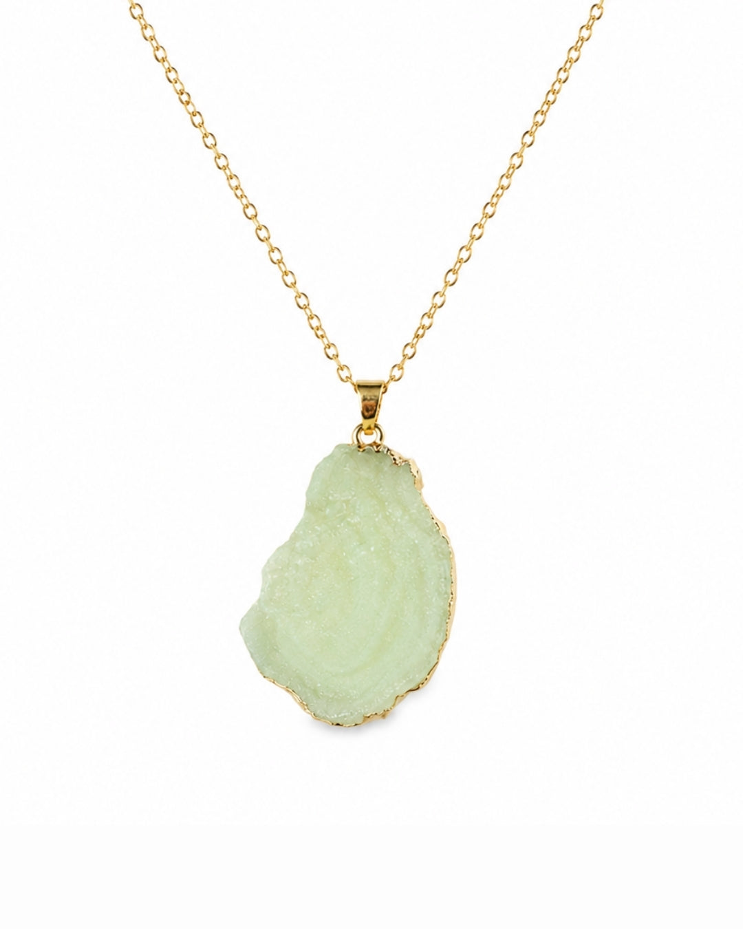 A gold chain necklace featuring a raw, irregular-shaped light green geode or druzy stone pendant with a gold border, shown against a plain white background.