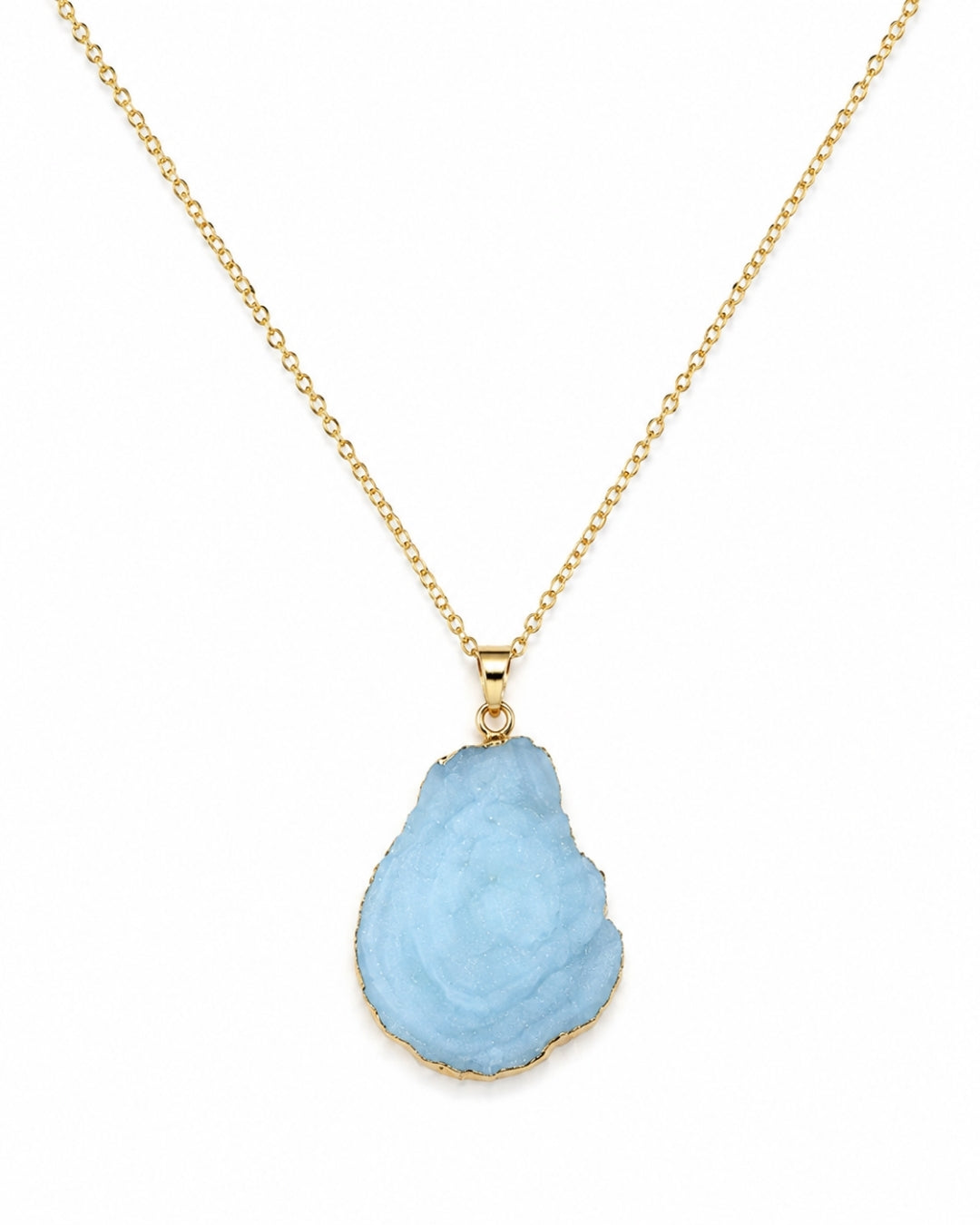 A gold chain necklace featuring a teardrop-shaped light blue raw gemstone pendant with a gold border, displayed against a solid white background.