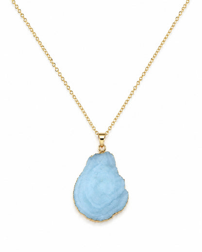 A gold chain necklace featuring a teardrop-shaped light blue raw gemstone pendant with a gold border, displayed against a solid white background.