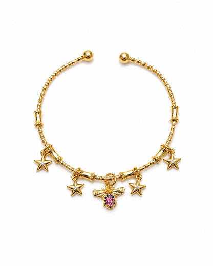 A gold-plated charm bracelet featuring five star charms and a central bee charm embellished with a pink gemstone, displayed on a clean white background.