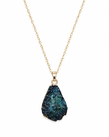 A gold chain necklace featuring a teardrop-shaped druzy gemstone pendant with a deep blue and green crystalline texture, set in a gold bezel on a plain white background.