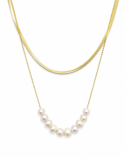 A double-layered gold necklace set on a white background, featuring a thick curved gold chain and a delicate gold beaded chain with a row of white freshwater pearls.
